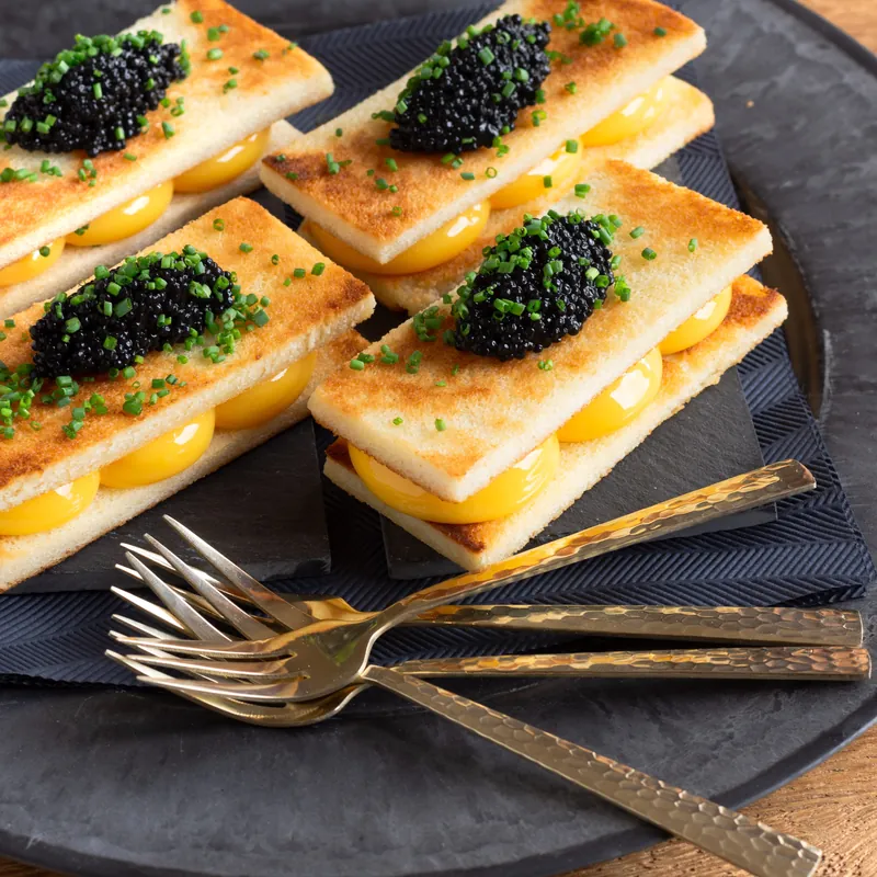 Kleine sandwiches met kaviaar, met gouden vorkjes ernaast